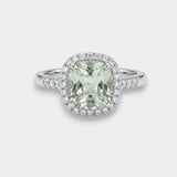 Ring with a green amethyst gemstone and diamond halo on a light gray background