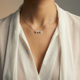 Necklace with three heart-shaped diamonds worn by a person in a white outfit.