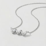White gold necklace with three heart-shaped gemstones on a light gray background