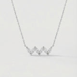 White gold necklace with three heart-shaped diamonds on a light gray background