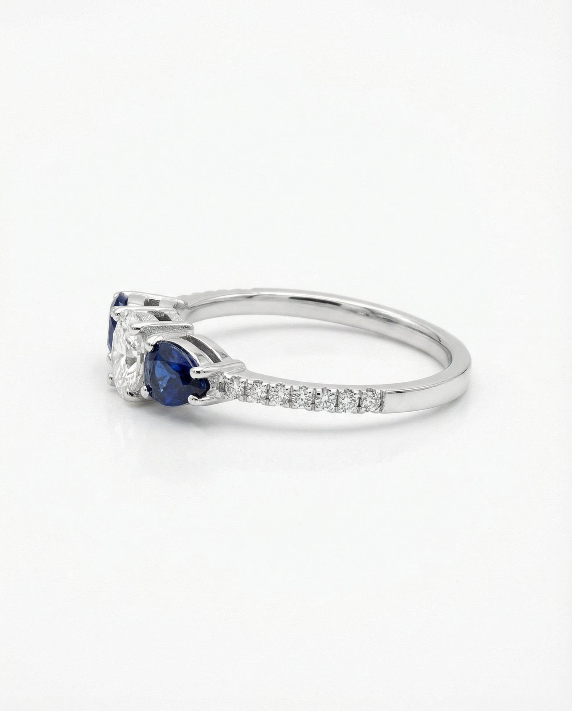 White gold ring with a diamond and blue sapphires on a white background