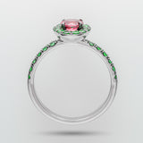 Ring with pink gemstone and green emerald accents on a white background