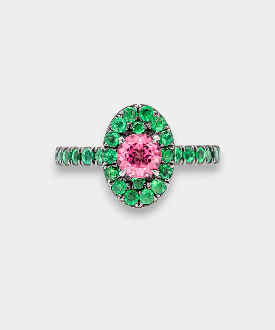 Ring with pink gemstone and green gemstones on a white background