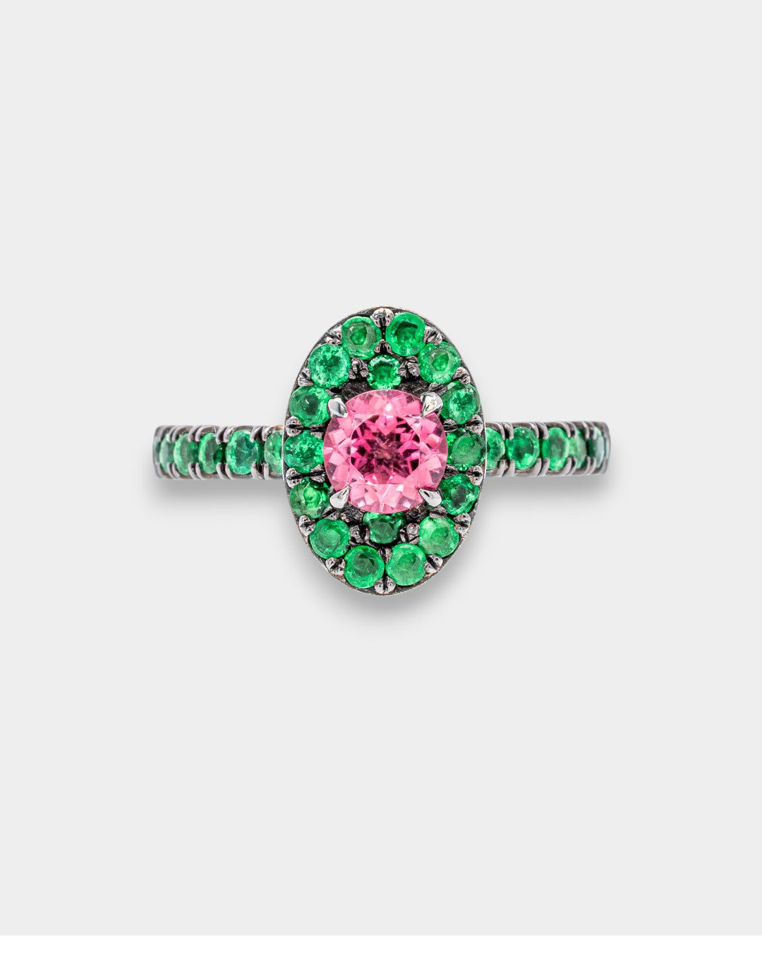 Ring with pink gemstone and green gemstones on a white background