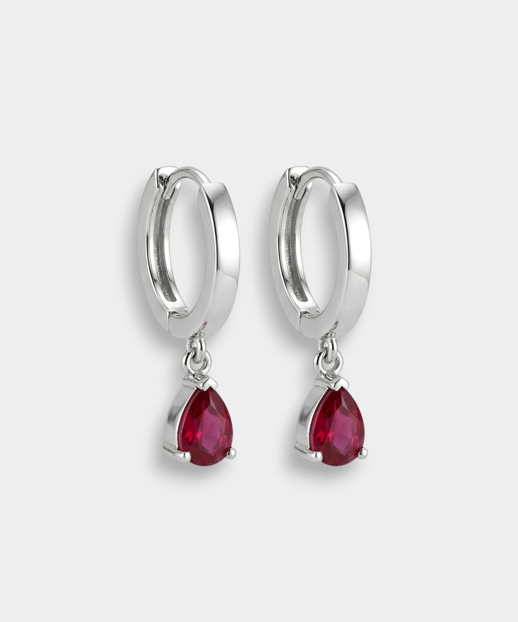 White gold hoop earrings with red rubies on a white background