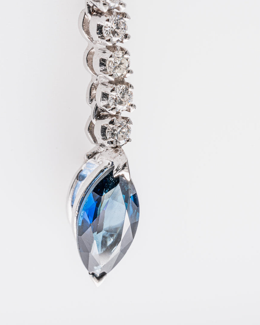 Diamond necklace with a blue teardrop sapphire pendant on a light gray background