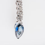 Diamond necklace with a blue teardrop sapphire pendant on a light gray background