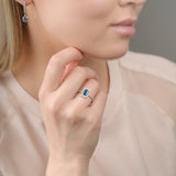 Close-up of a woman wearing a sapphire gemstone ring and earrings.