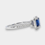 Diamond halo ring with a blue sapphire on a white background