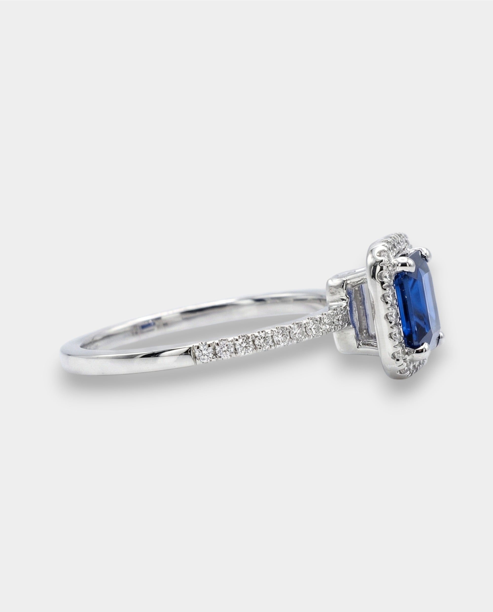 Diamond halo ring with a blue sapphire on a white background