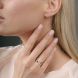 Woman wearing a ring with sapphires on her finger with a neutral background