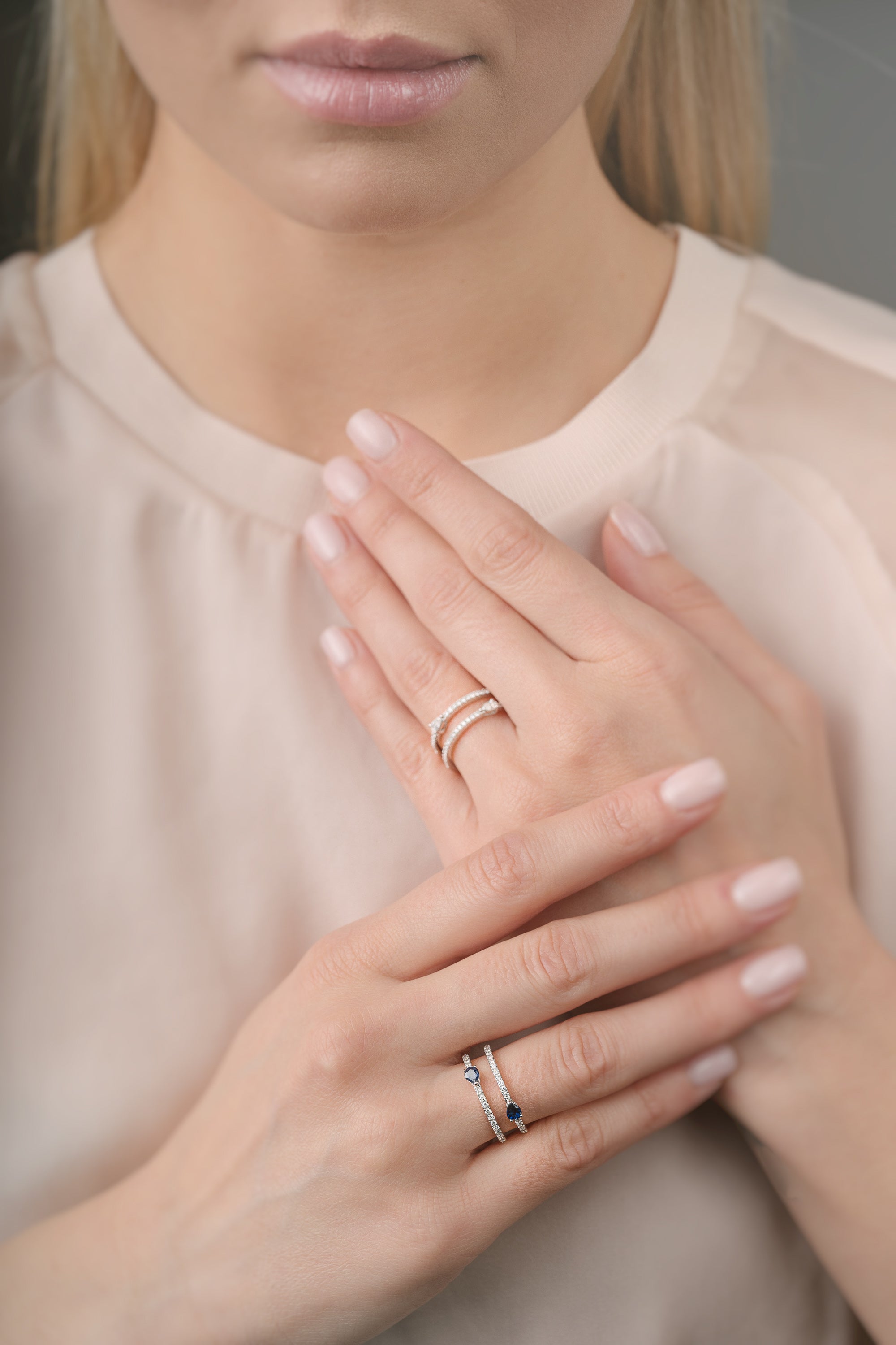 Close-up of a person wearing two rings on their fingers with a neutral background