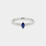 Ring with a blue sapphire and diamond accents on a light gray background