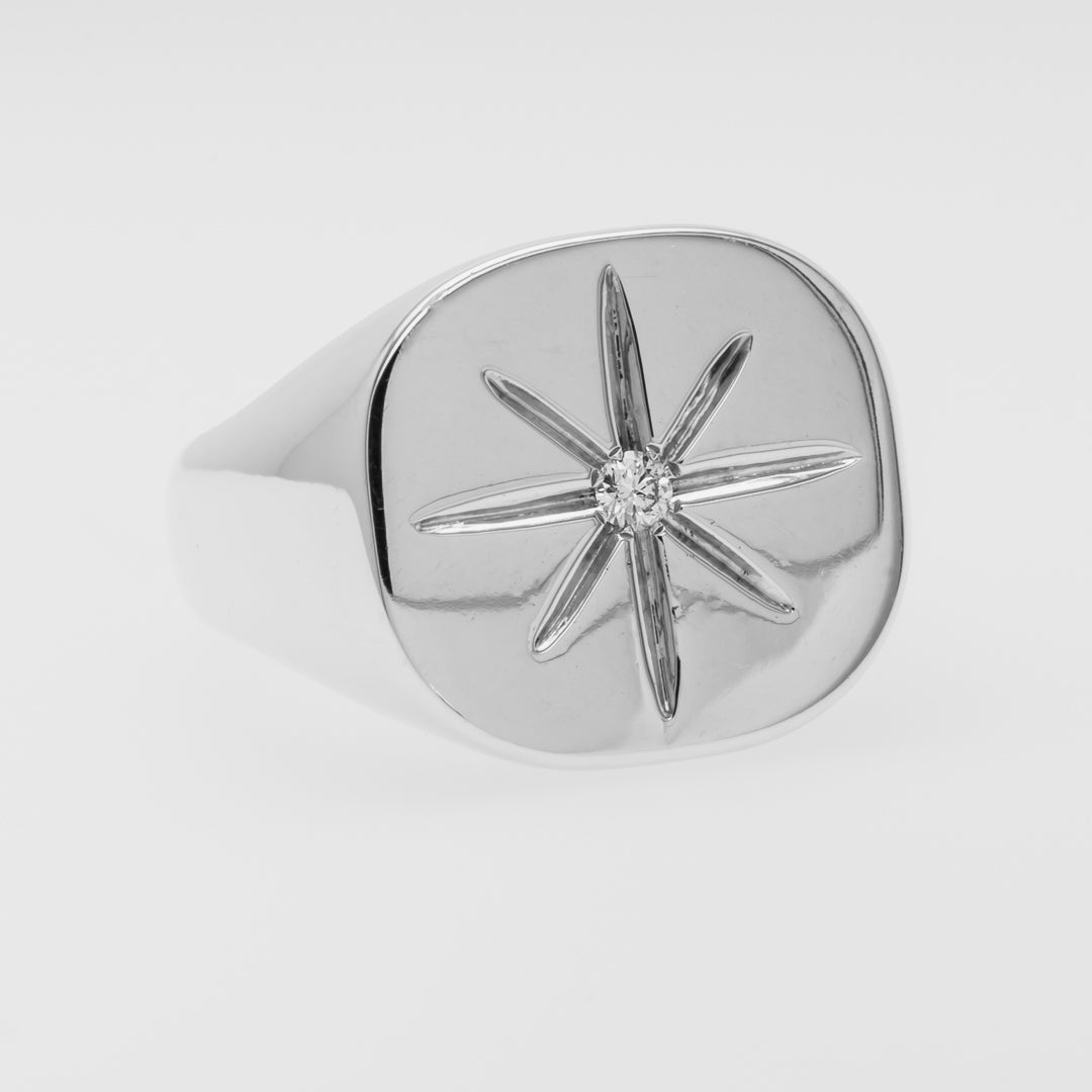 White gold ring with star design on a light gray background