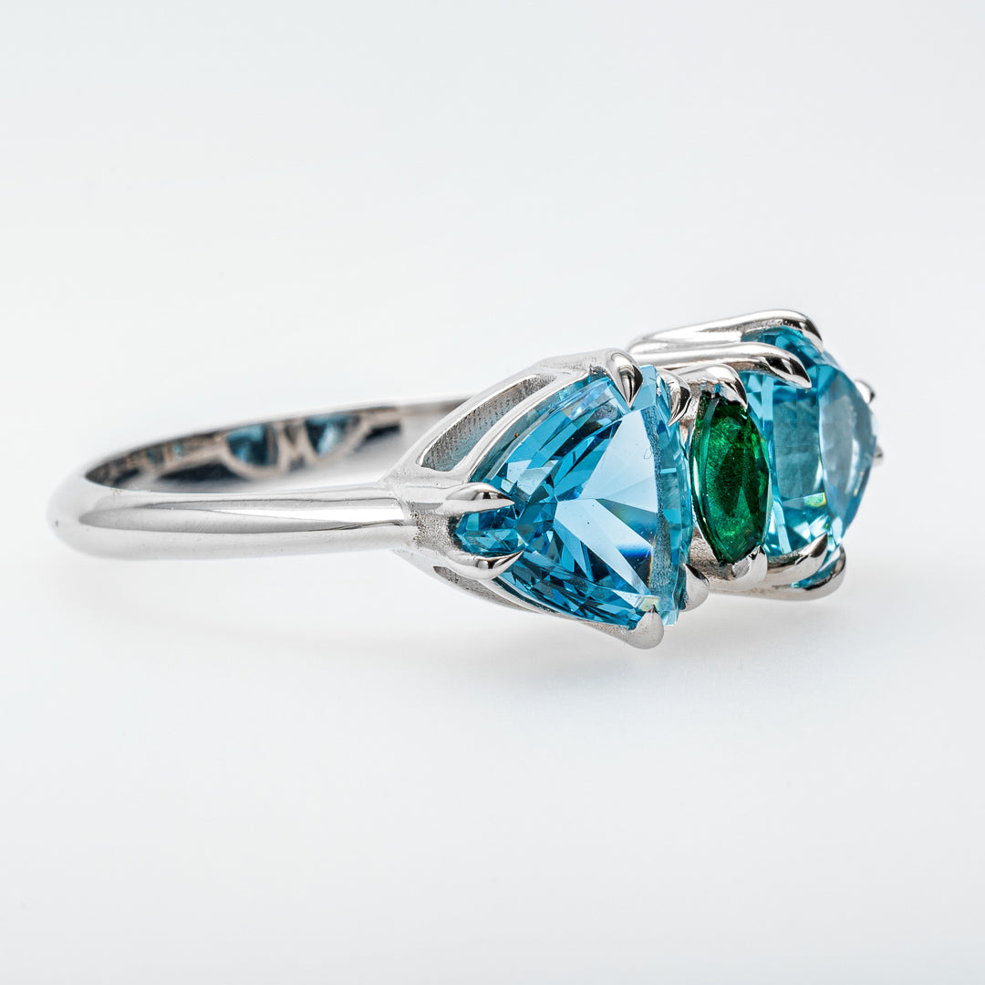 Silver ring with blue and green gemstones on a white background