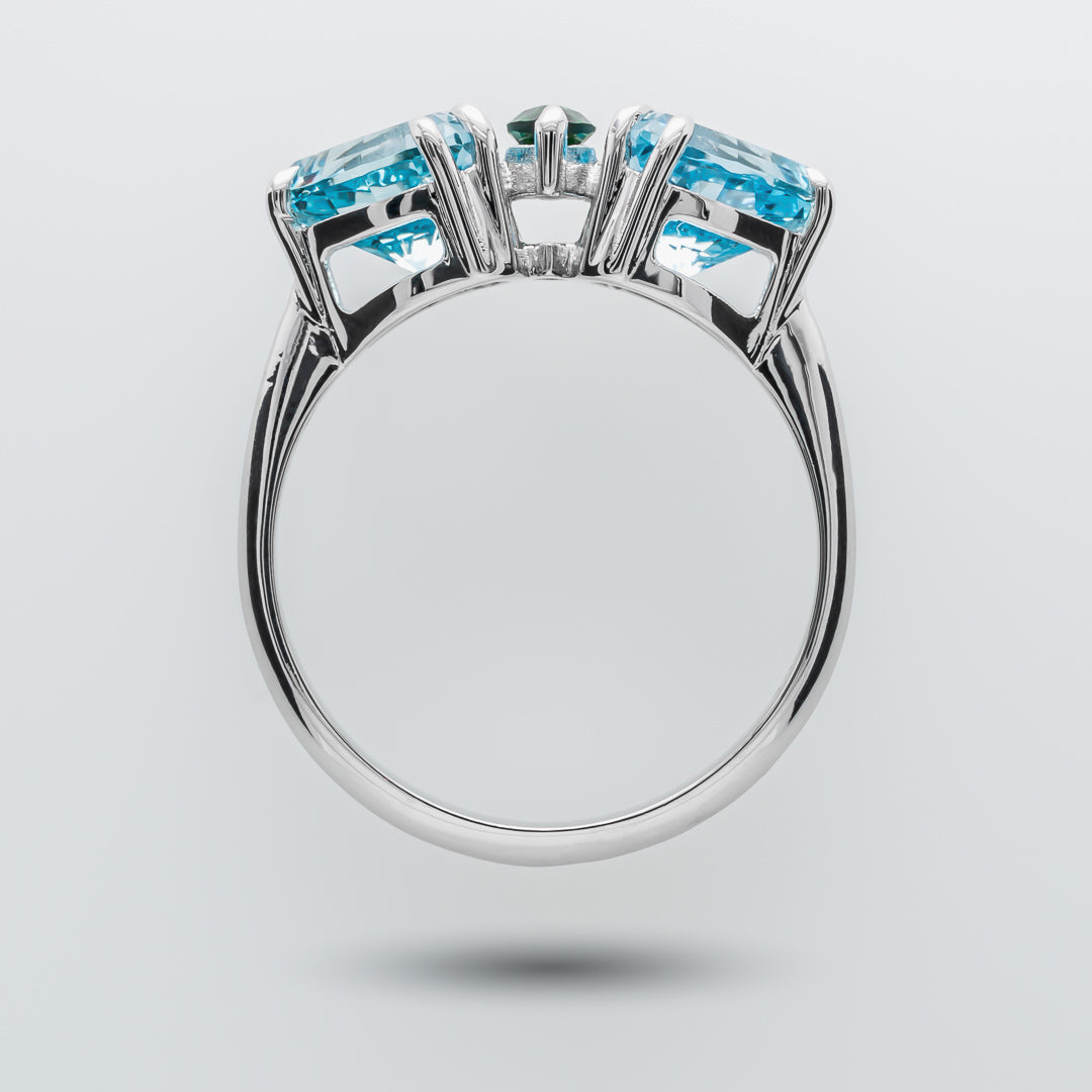 White gold ring with blue and green gemstones on a light gray background