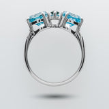 White gold ring with blue and green gemstones on a light gray background