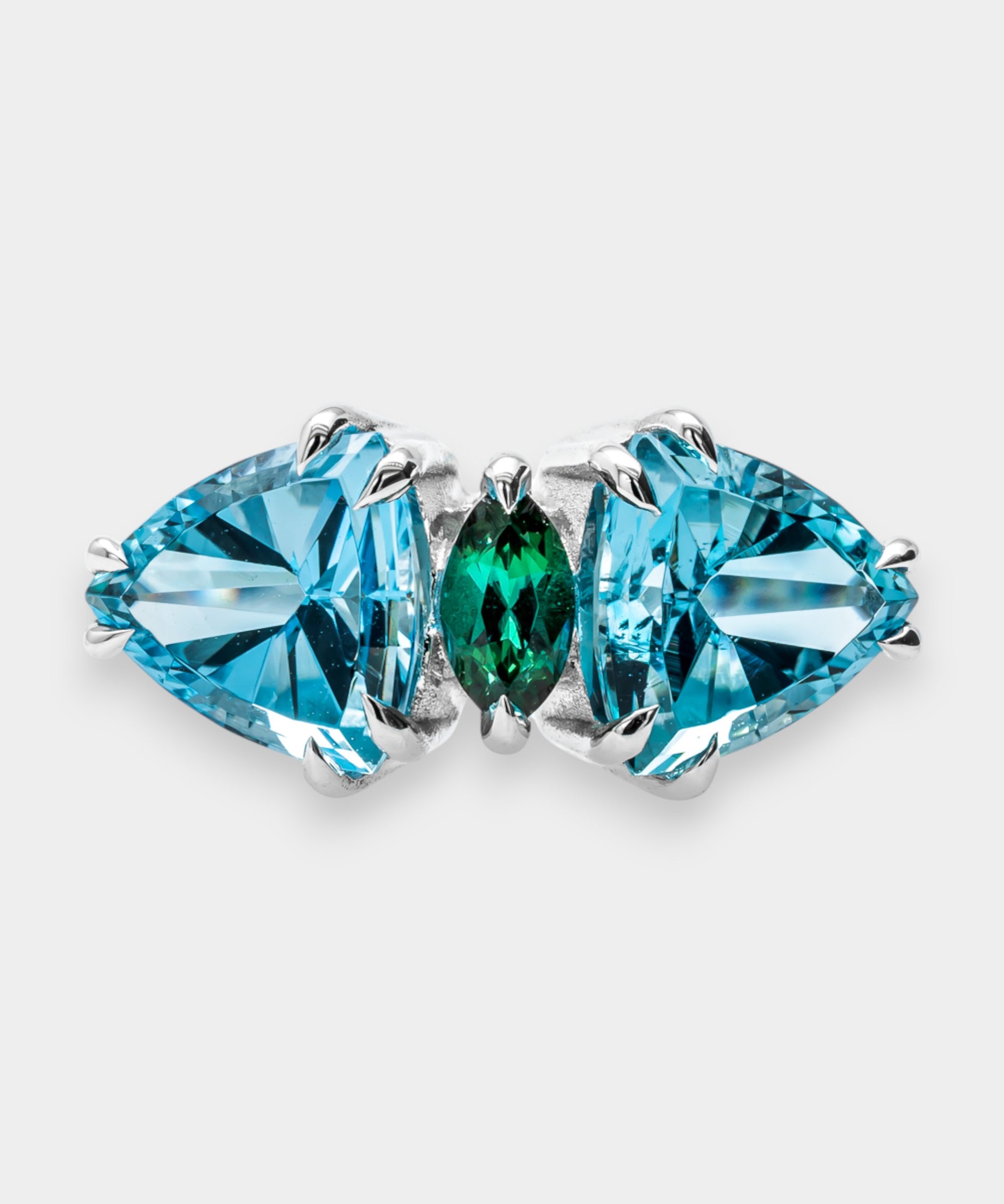 A ring with blue and green gemstones on a light gray background