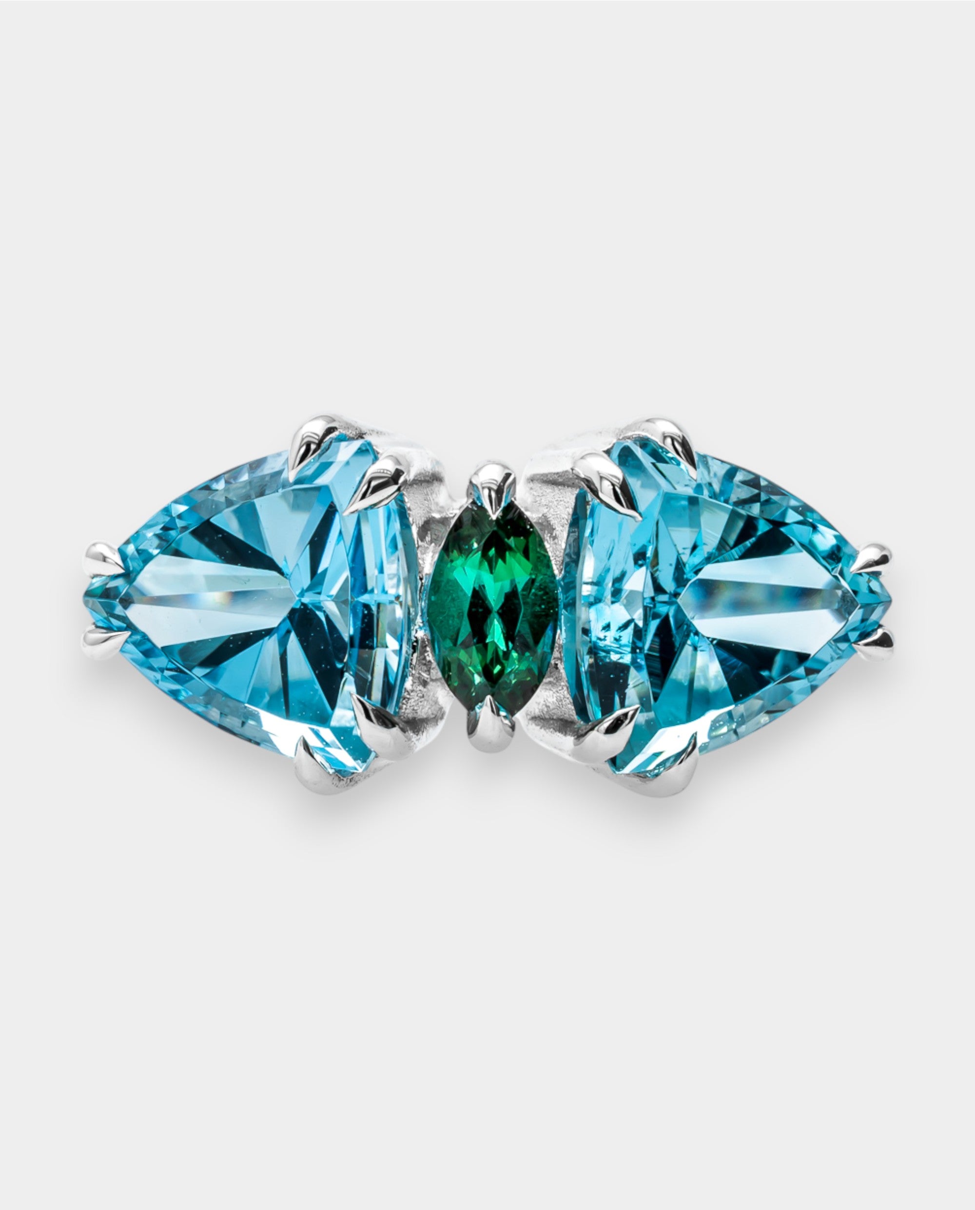 A ring with blue and green gemstones on a light gray background