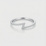 White gold z-shaped ring with diamond accents on a light gray background