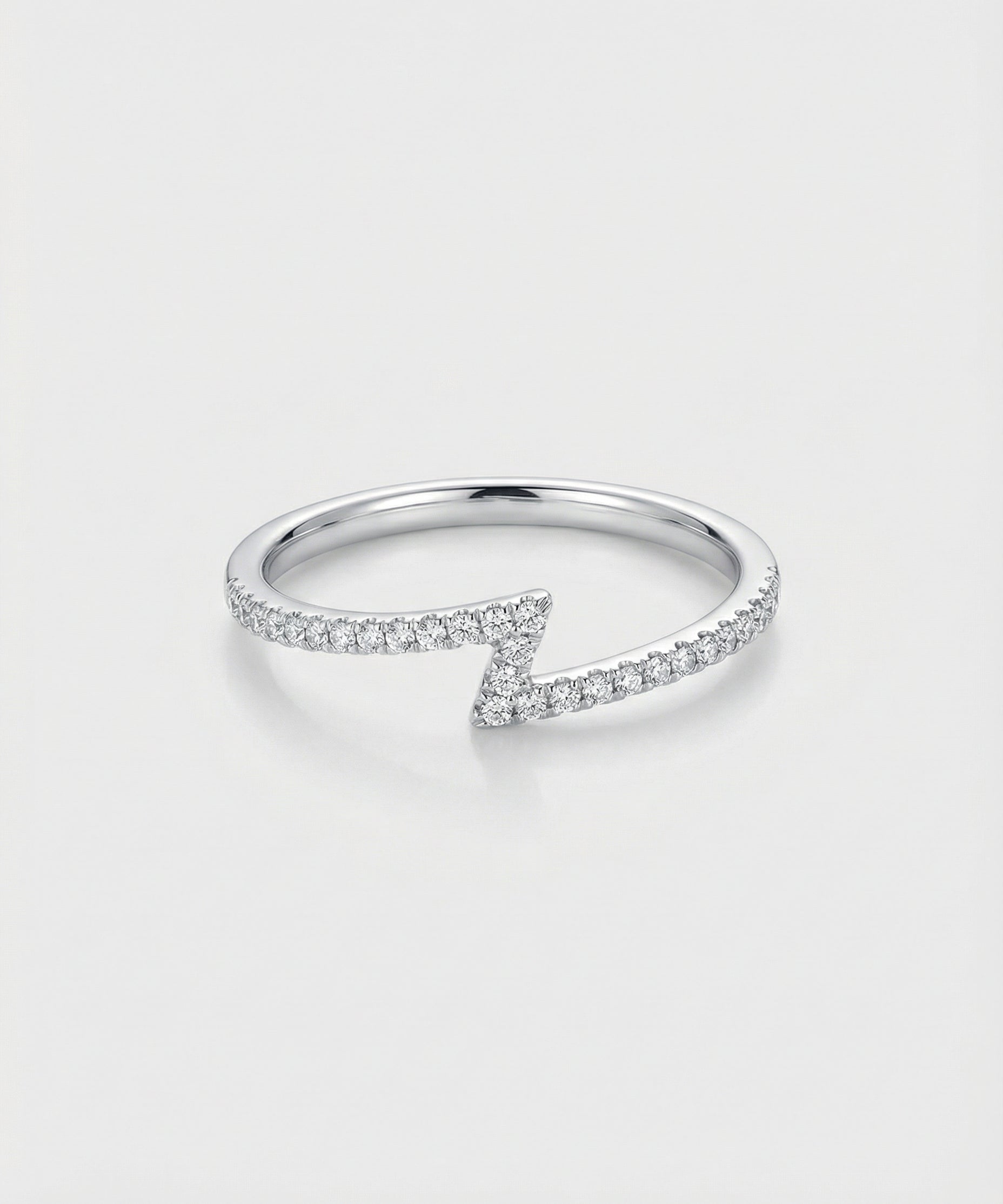White gold z-shaped ring with diamond accents on a light gray background