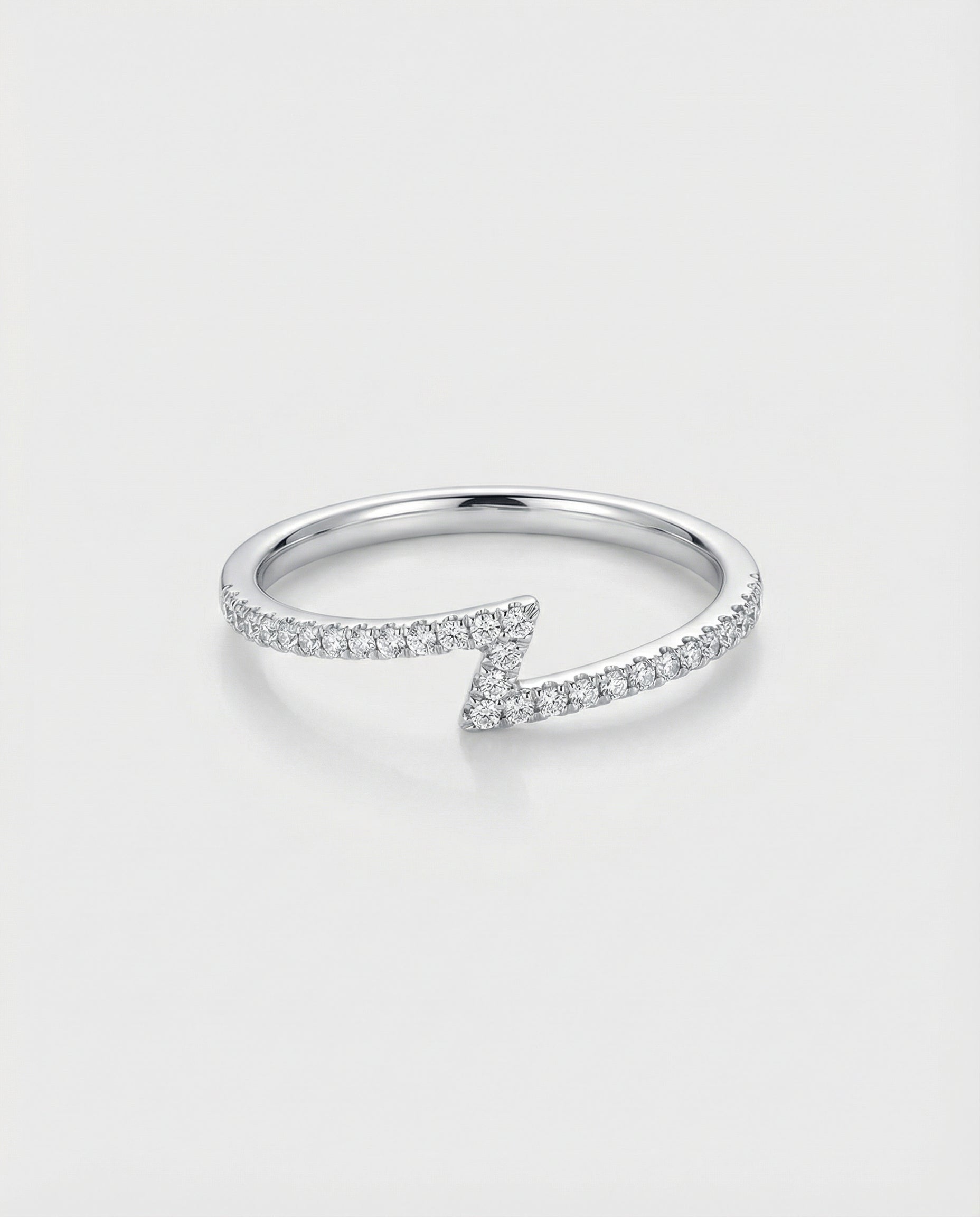White gold z-shaped ring with diamond accents on a light gray background