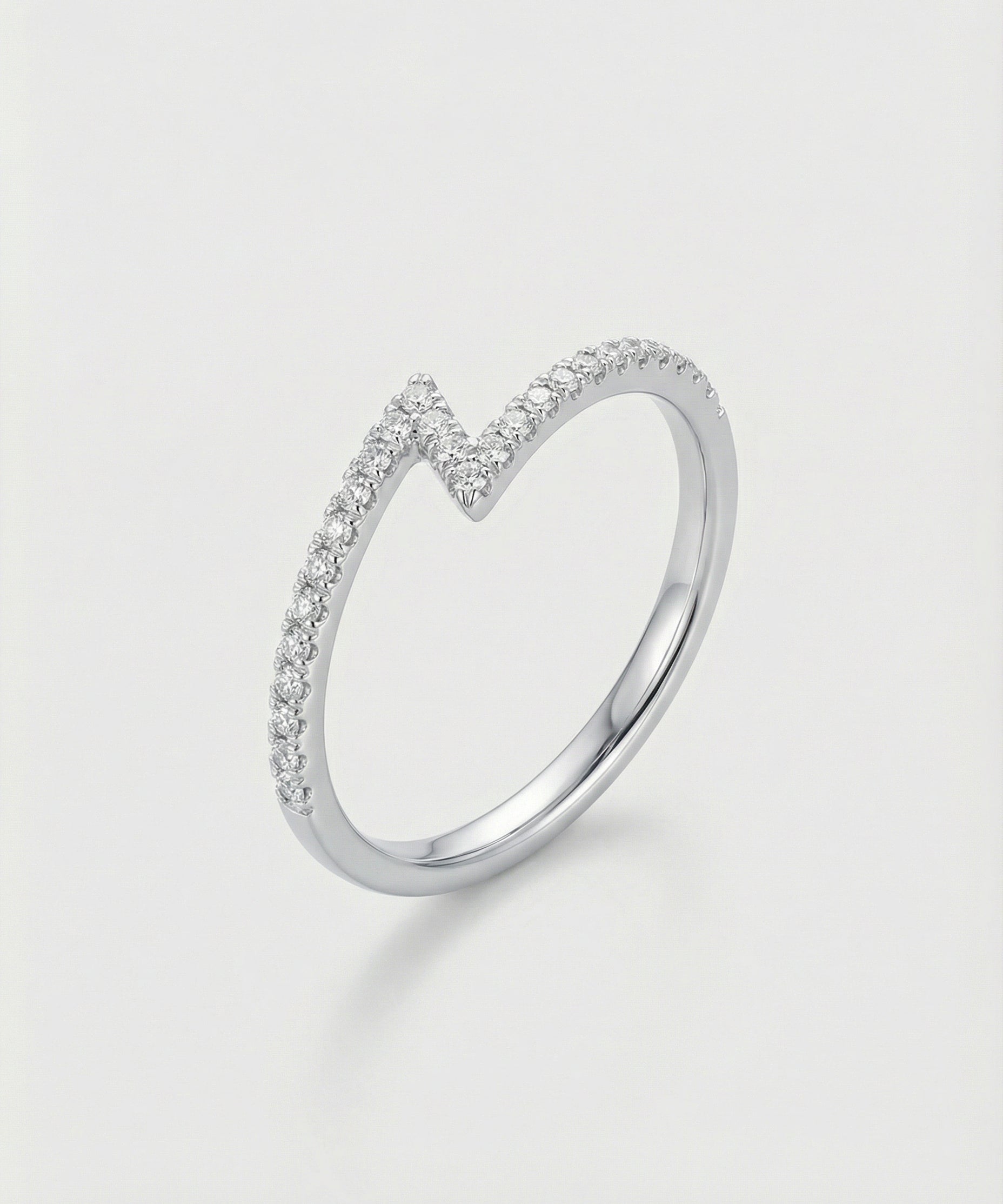 White gold z-shaped ring with small diamonds on a light gray background