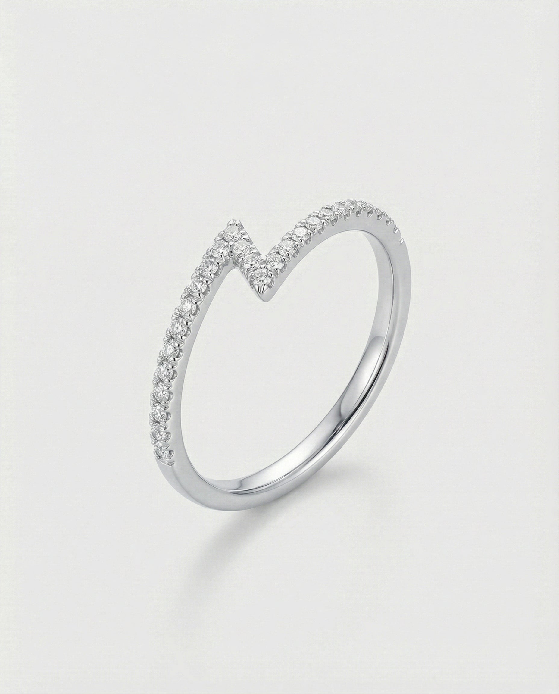 White gold z-shaped ring with small diamonds on a light gray background