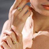 Close-up of a person wearing two yellow gemstone rings on fingers with a blurred background