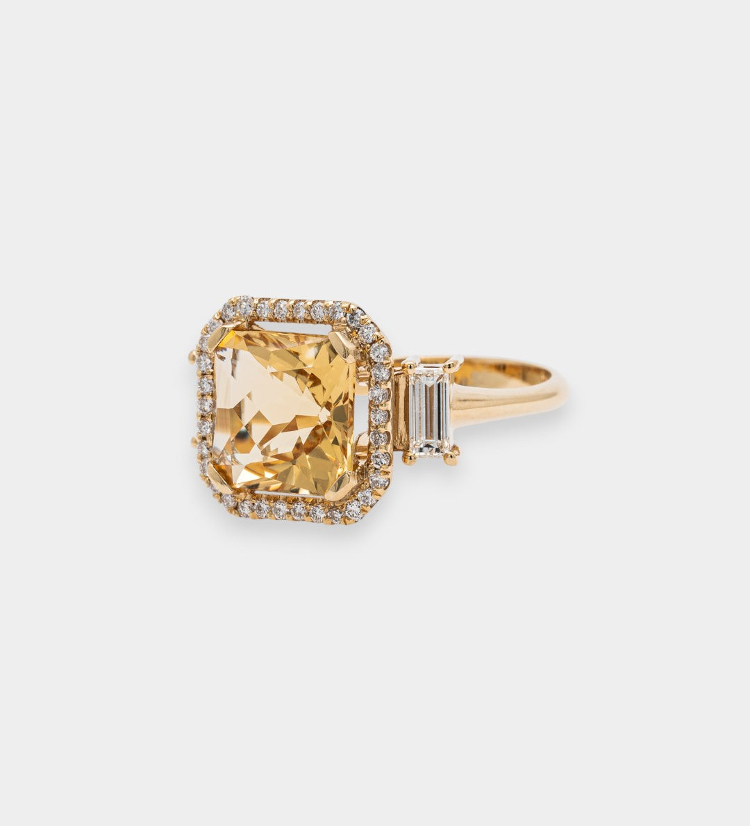 Gold ring with a large yellow beryl gemstone on a light gray background