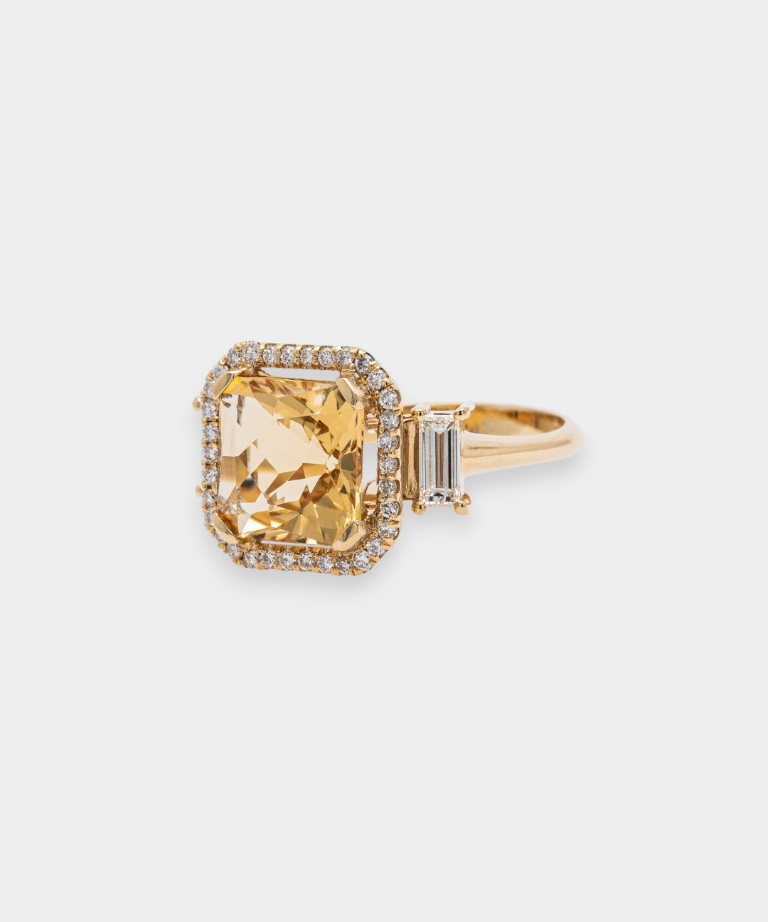 Gold ring with a large yellow beryl gemstone on a light gray background