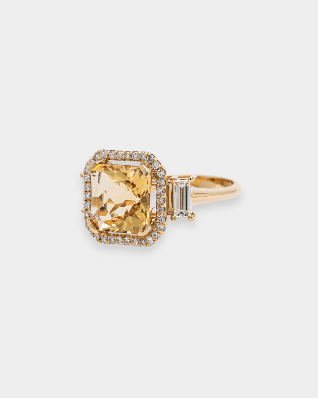 Gold ring with a large yellow beryl gemstone on a light gray background