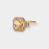 Gold ring with a large yellow beryl gemstone on a light gray background