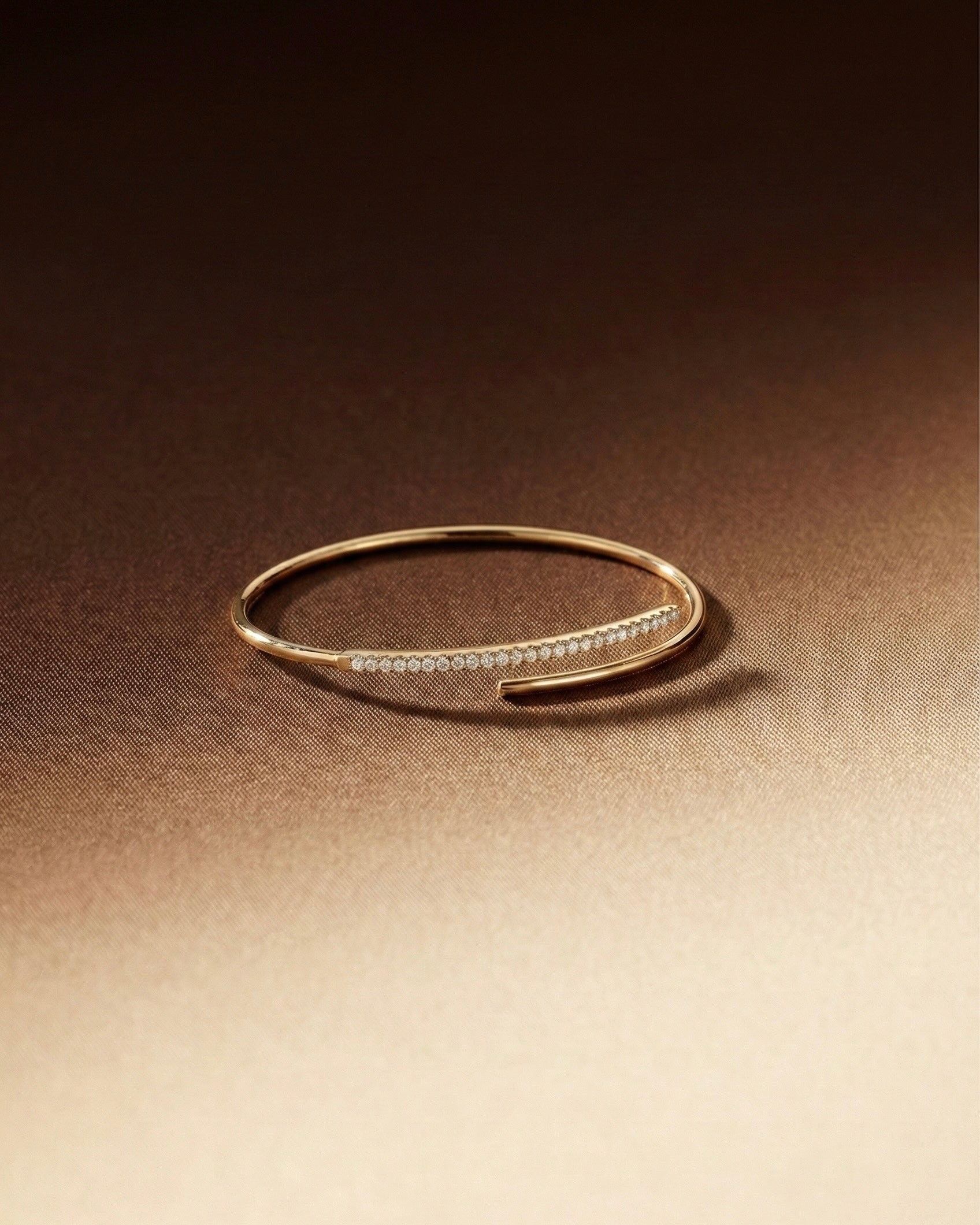 Gold bracelet with small stones on a gradient brown background