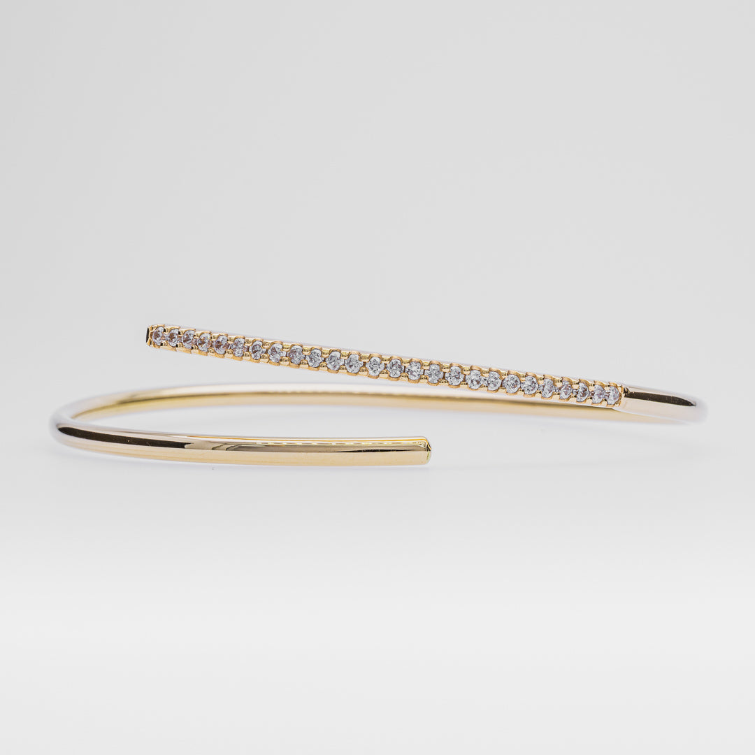 Gold bracelet with small diamonds on a light gray background