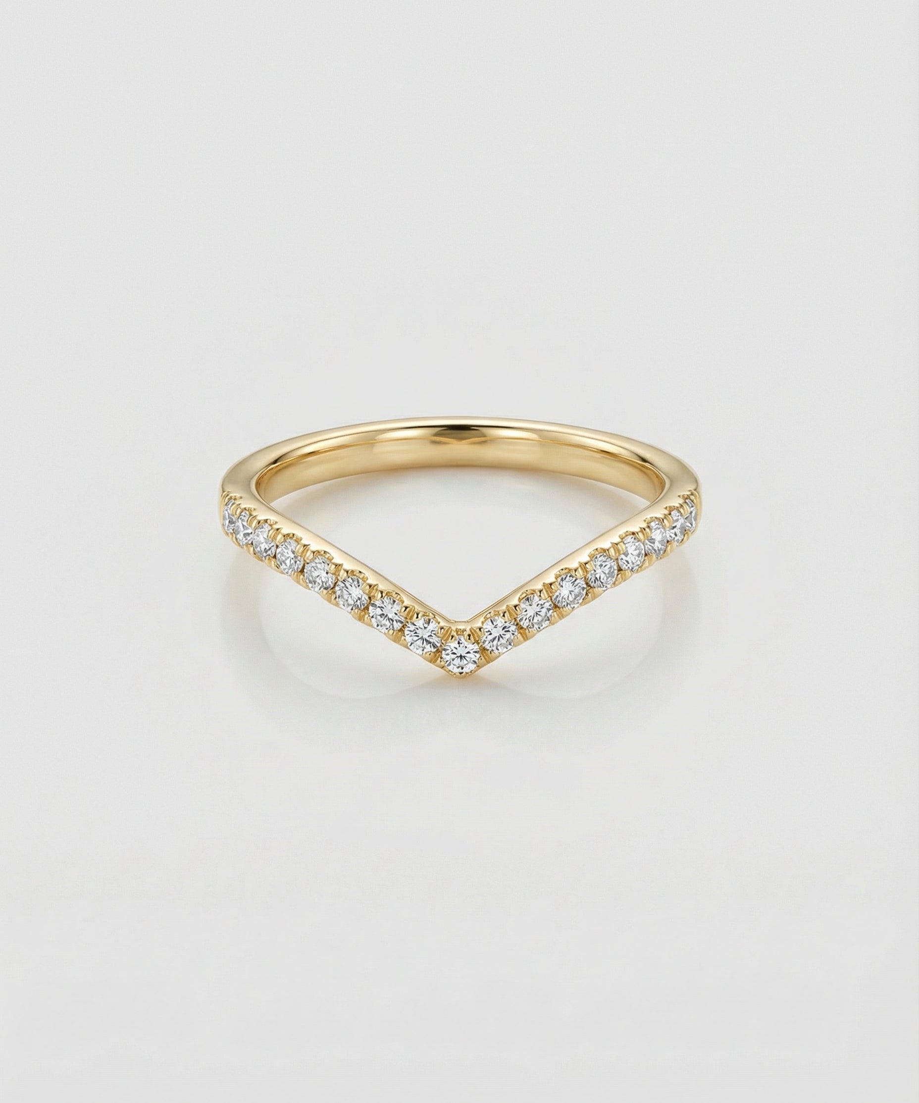 Gold chevron ring with diamond accents on a light gray background