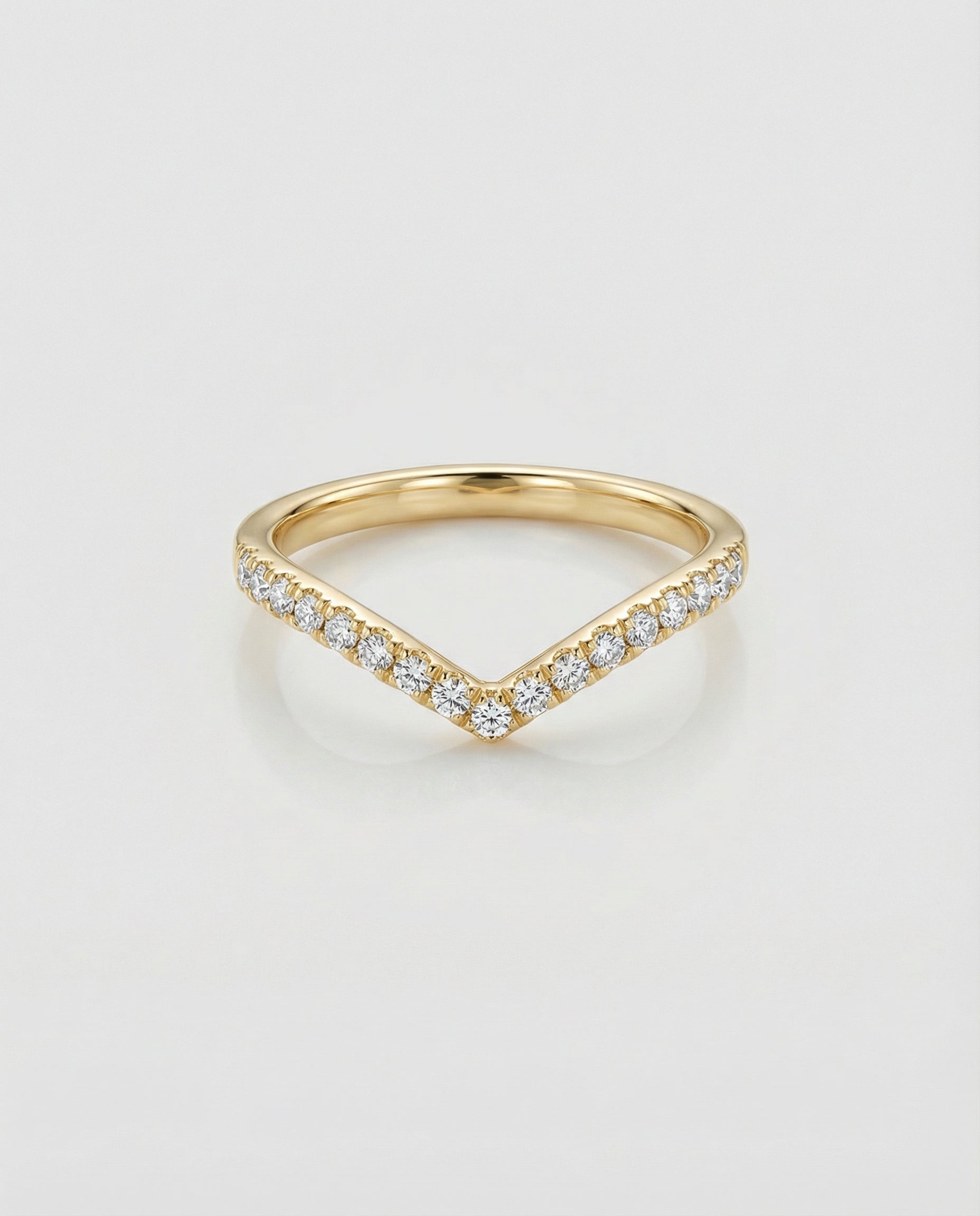 Gold chevron ring with diamond accents on a light gray background