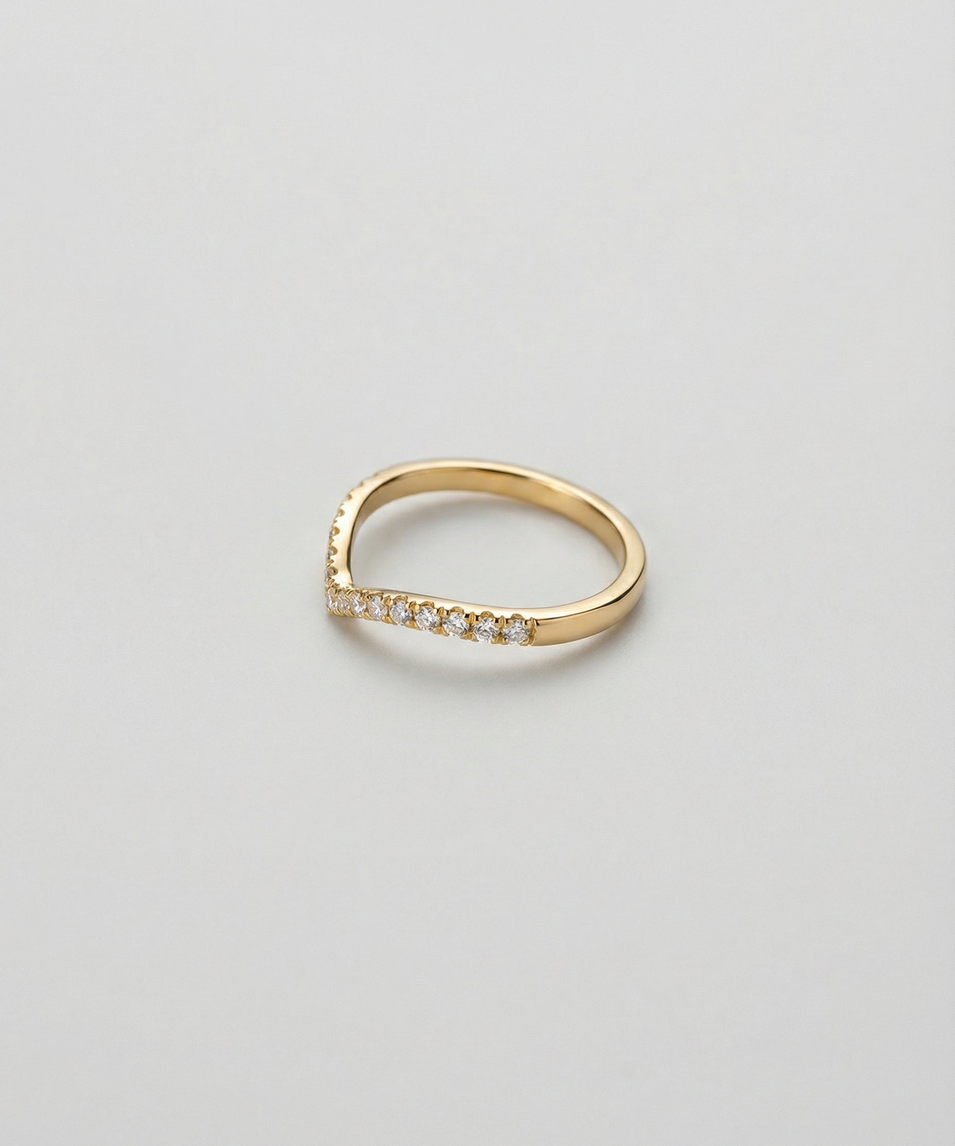 Gold ring with chevron band and small diamonds on a light gray background