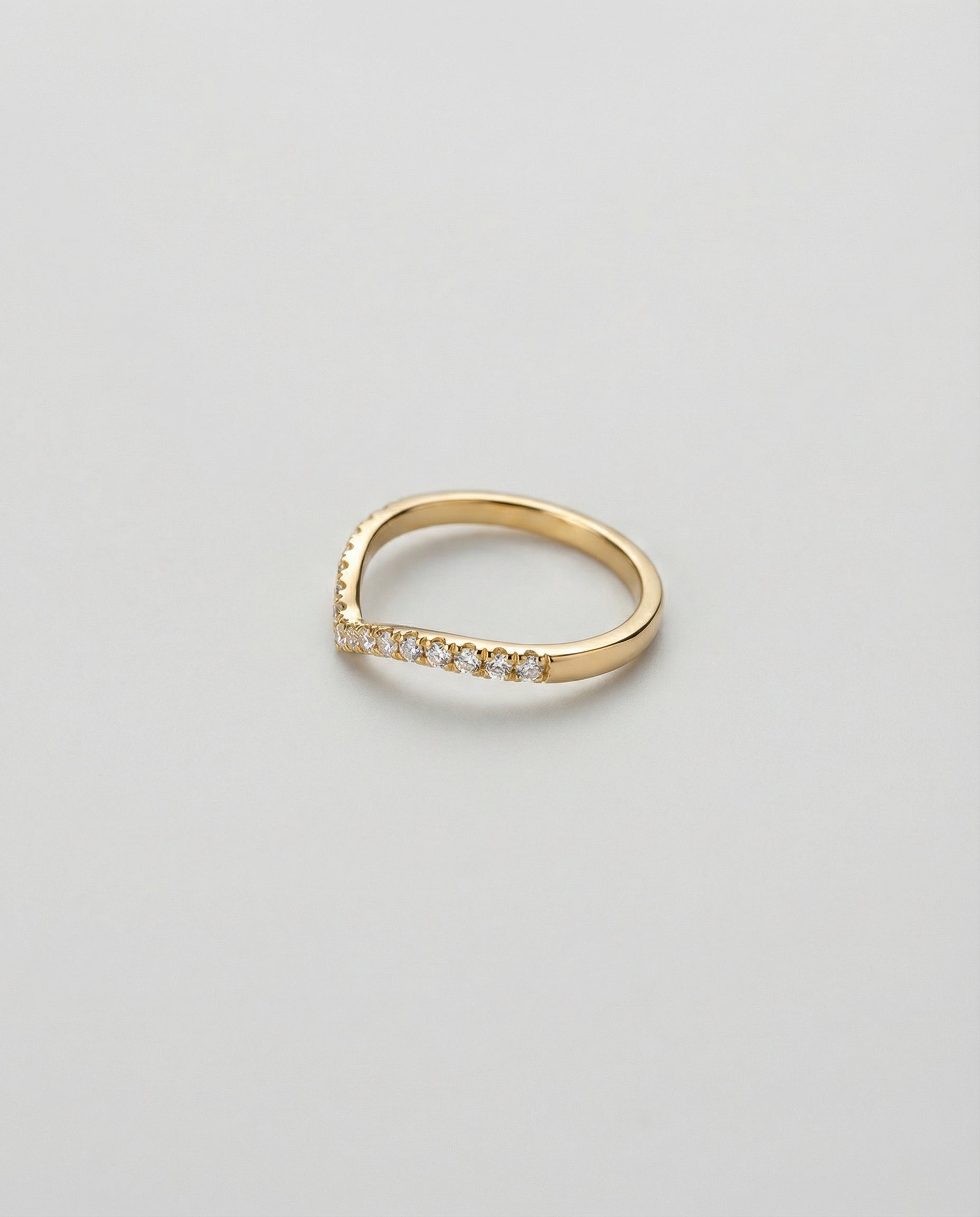Gold ring with chevron band and small diamonds on a light gray background