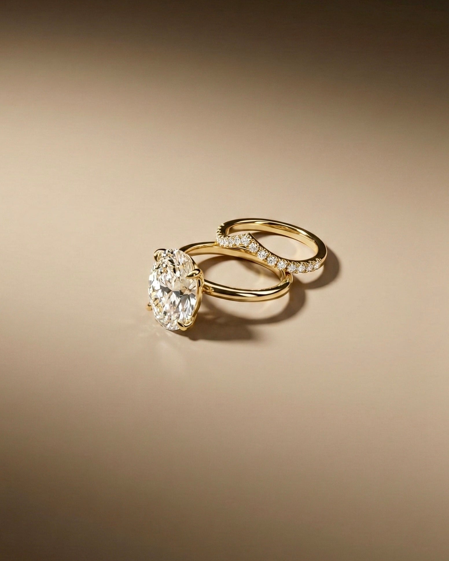 Two gold rings with diamond accents on a beige background