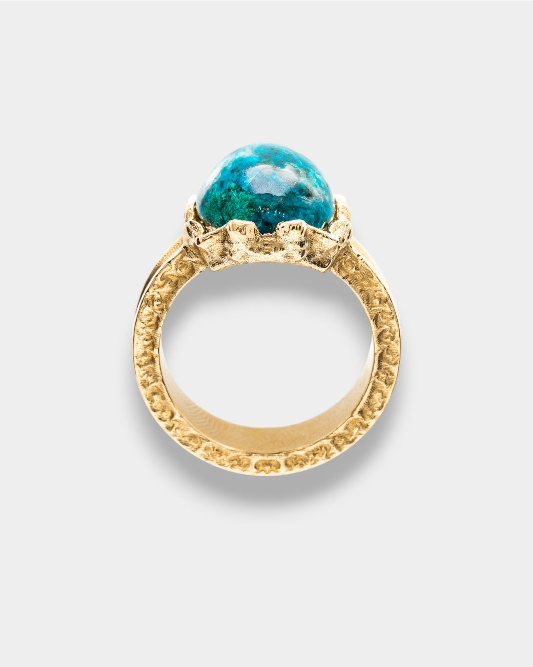 Gold ring with a blue natural gemstone on a light gray background
