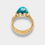 Gold ring with a blue natural gemstone on a light gray background