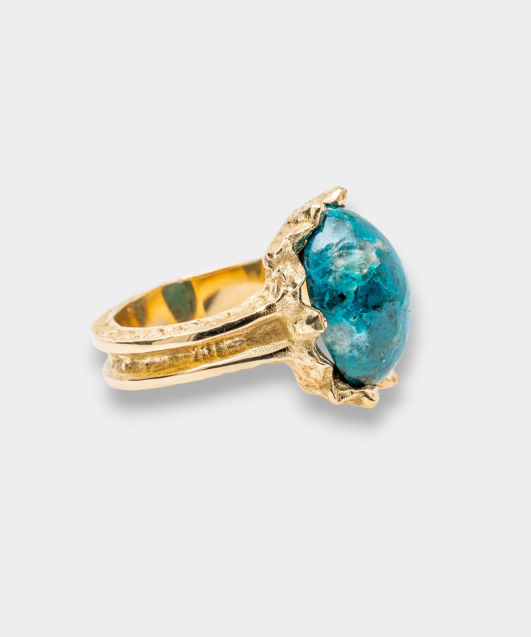 Gold ring with a blue gemstone on a light gray background