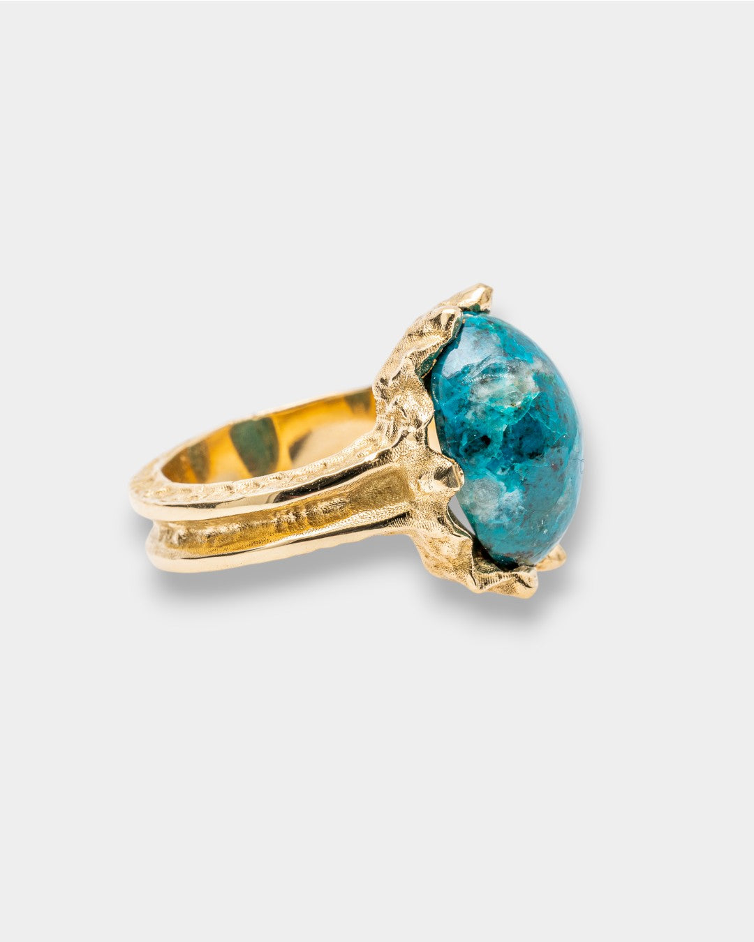 Gold ring with a blue gemstone on a light gray background