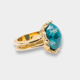 Gold ring with a blue gemstone on a light gray background