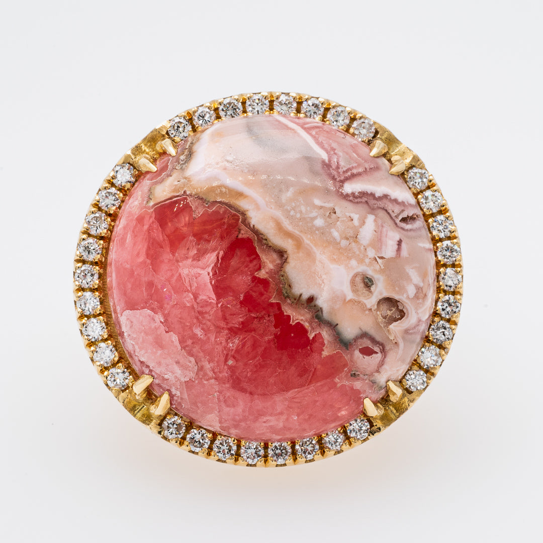 Jewelry with pink stone and diamond-studded gold border on a white background