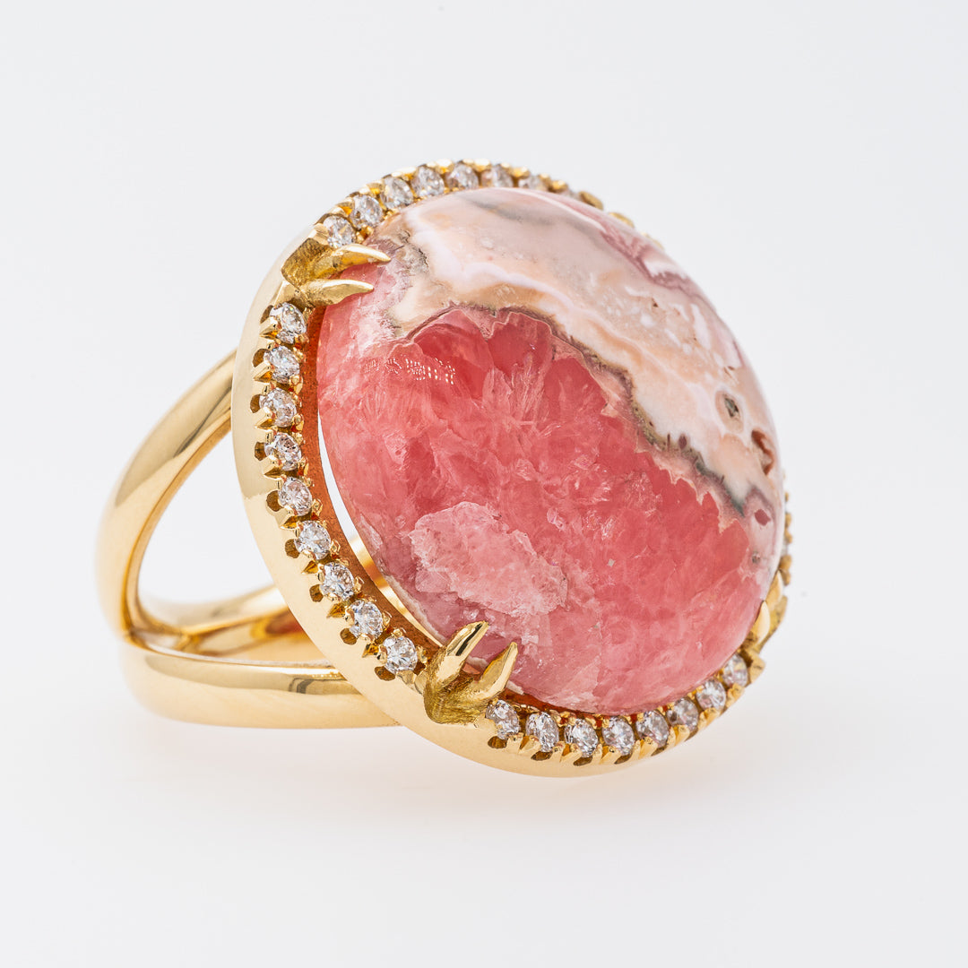 Gold ring with a pink stone and diamond accents on a white background