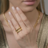 Close-up of a person wearing gold jewelry including a ring and necklace.