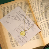 Gold necklace with a pendant on a card over an open book