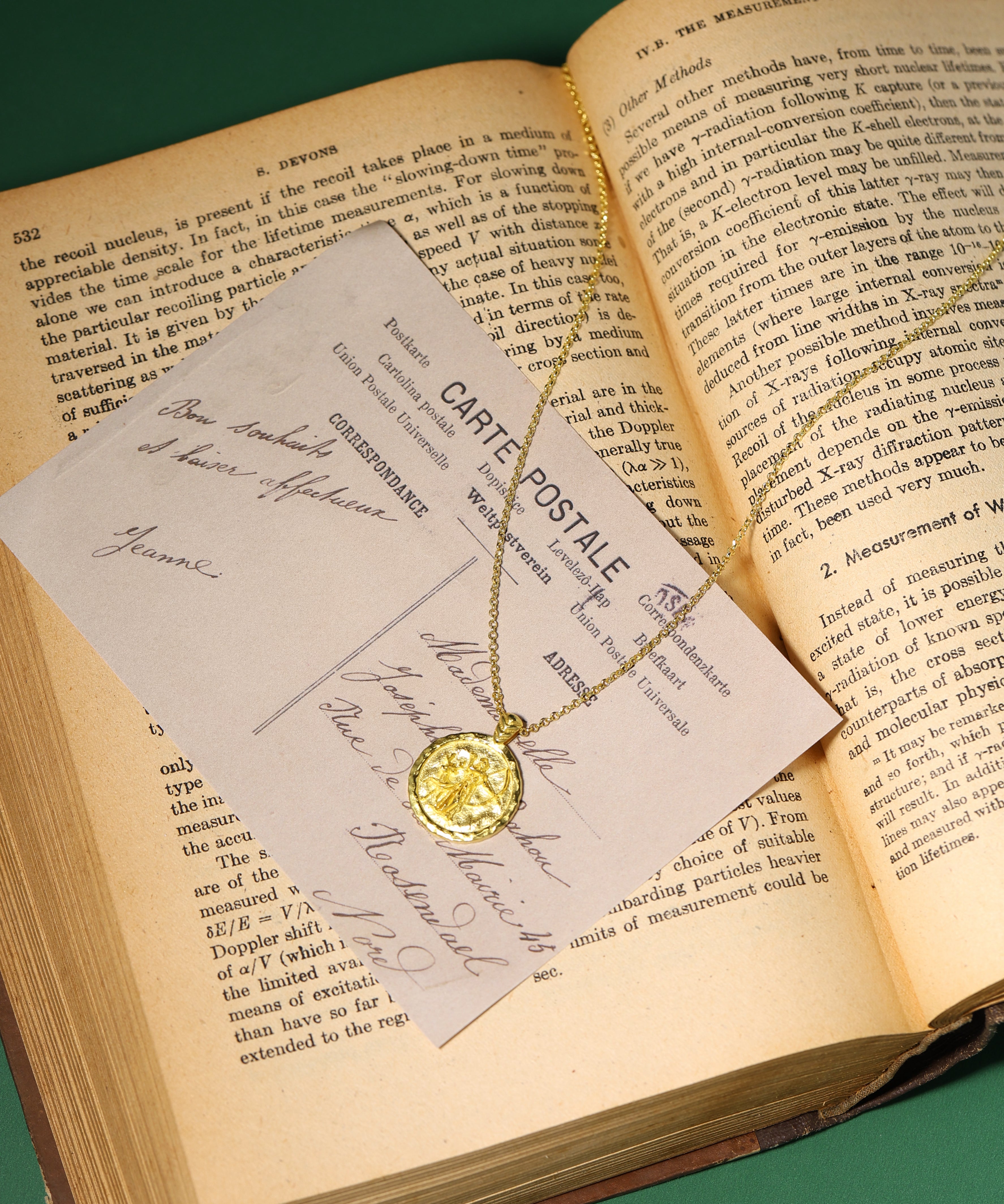 Gold necklace with a pendant on a card over an open book